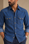 Close-up of The Western Edit cotton denim shirt showing contrast topstitching and two brass-tone buttons on each chest pocket flap.