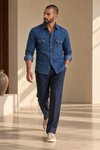 ARTLESS The Western Edit indigo denim shirt worn with navy trousers, front walking view.